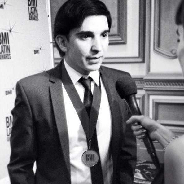 Man in a suit speaking into a microphone at an event.