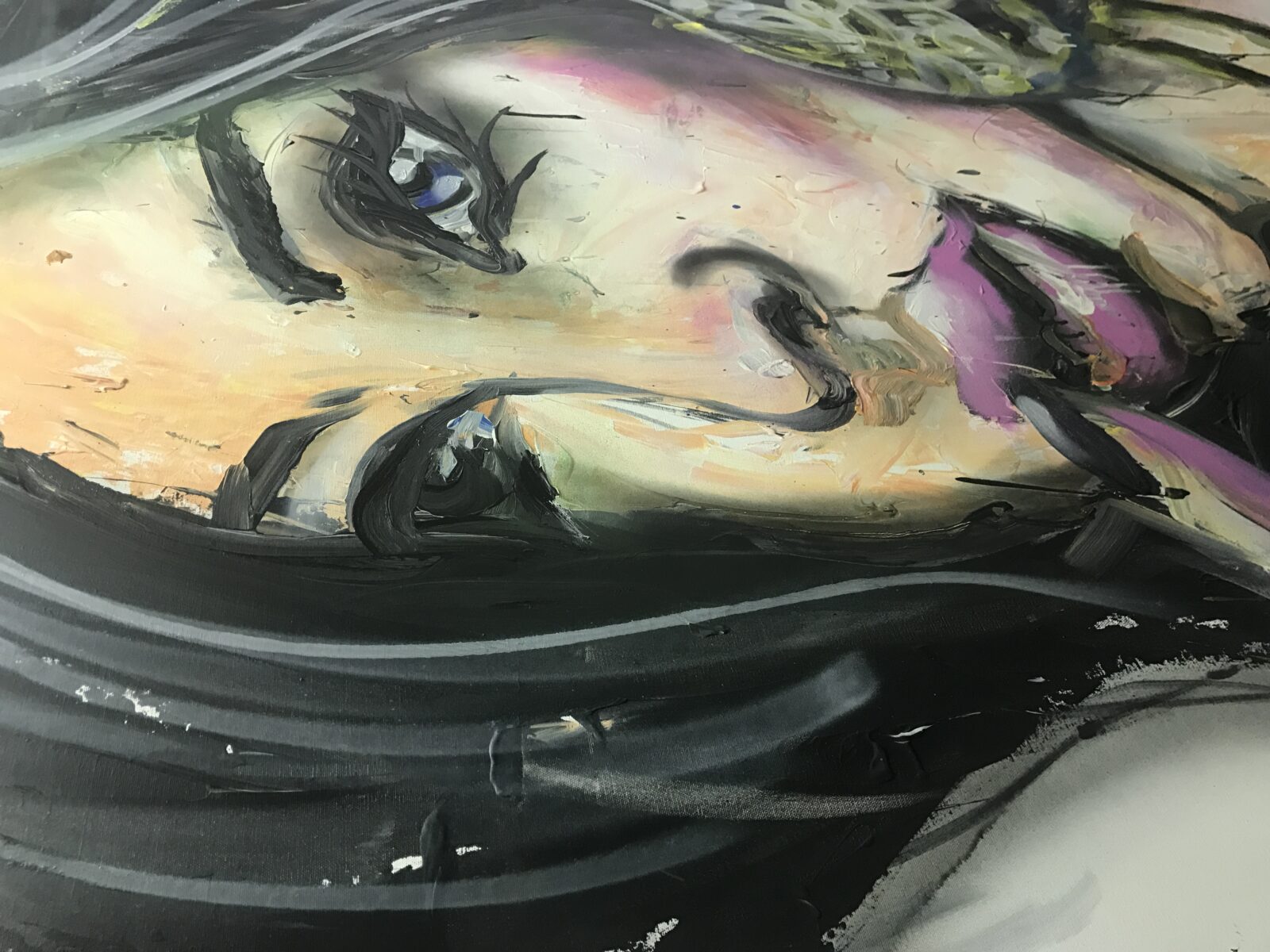 Close-up of a mural featuring a woman's face with expressive eyes and colorful shading.