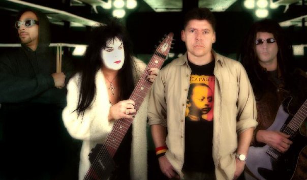Two individuals, one with white face paint holding a guitar, the other in casual clothes.