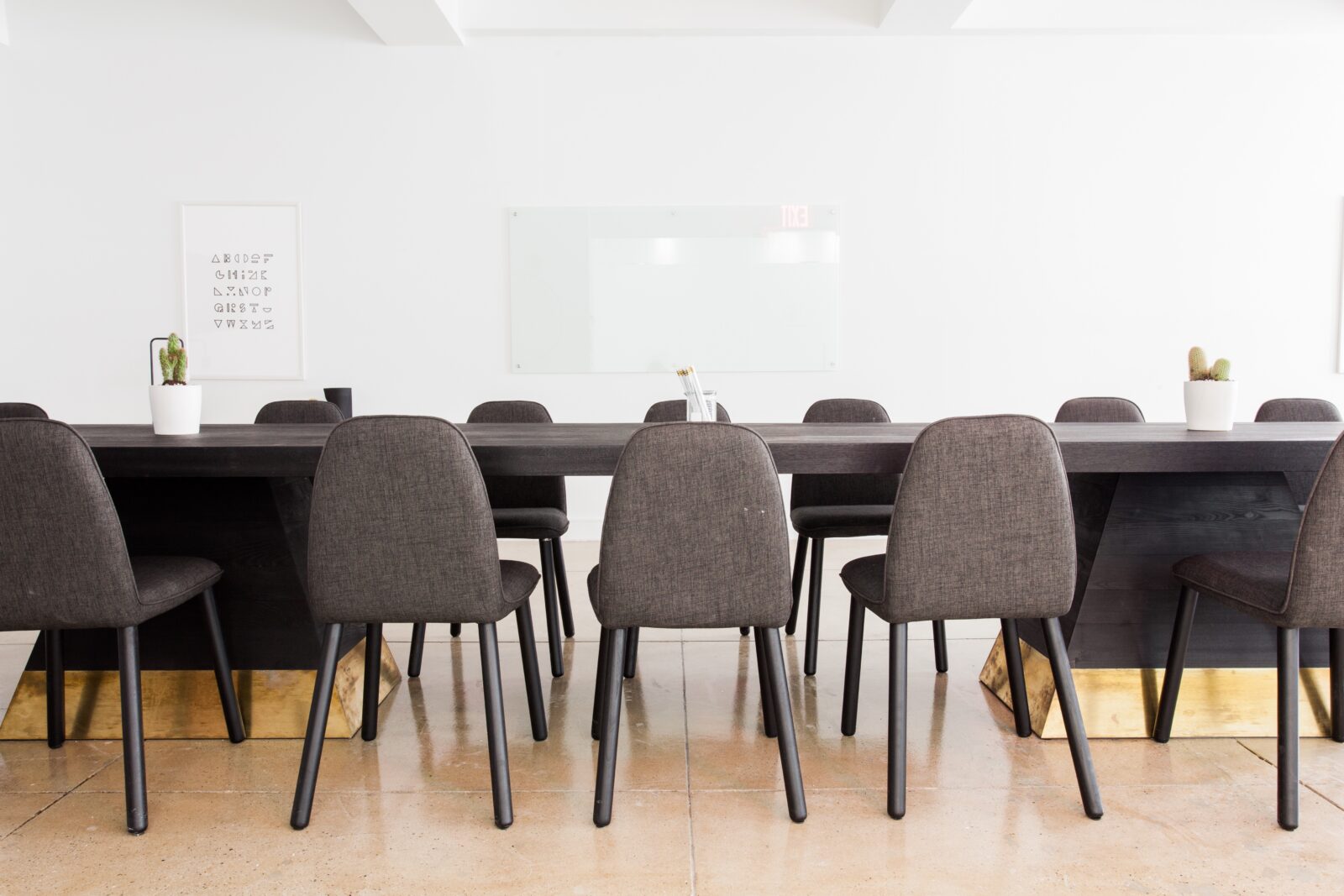 Modern conference room with a long table and gray upholstered chairs.