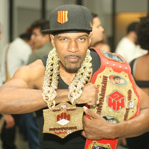 Man with championship belt and chains poses confidently.
